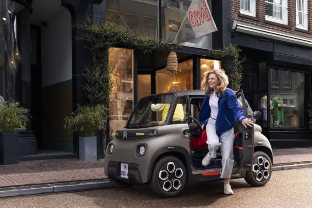 Una donna scende da una Citroen Ami parcheggiata in strada