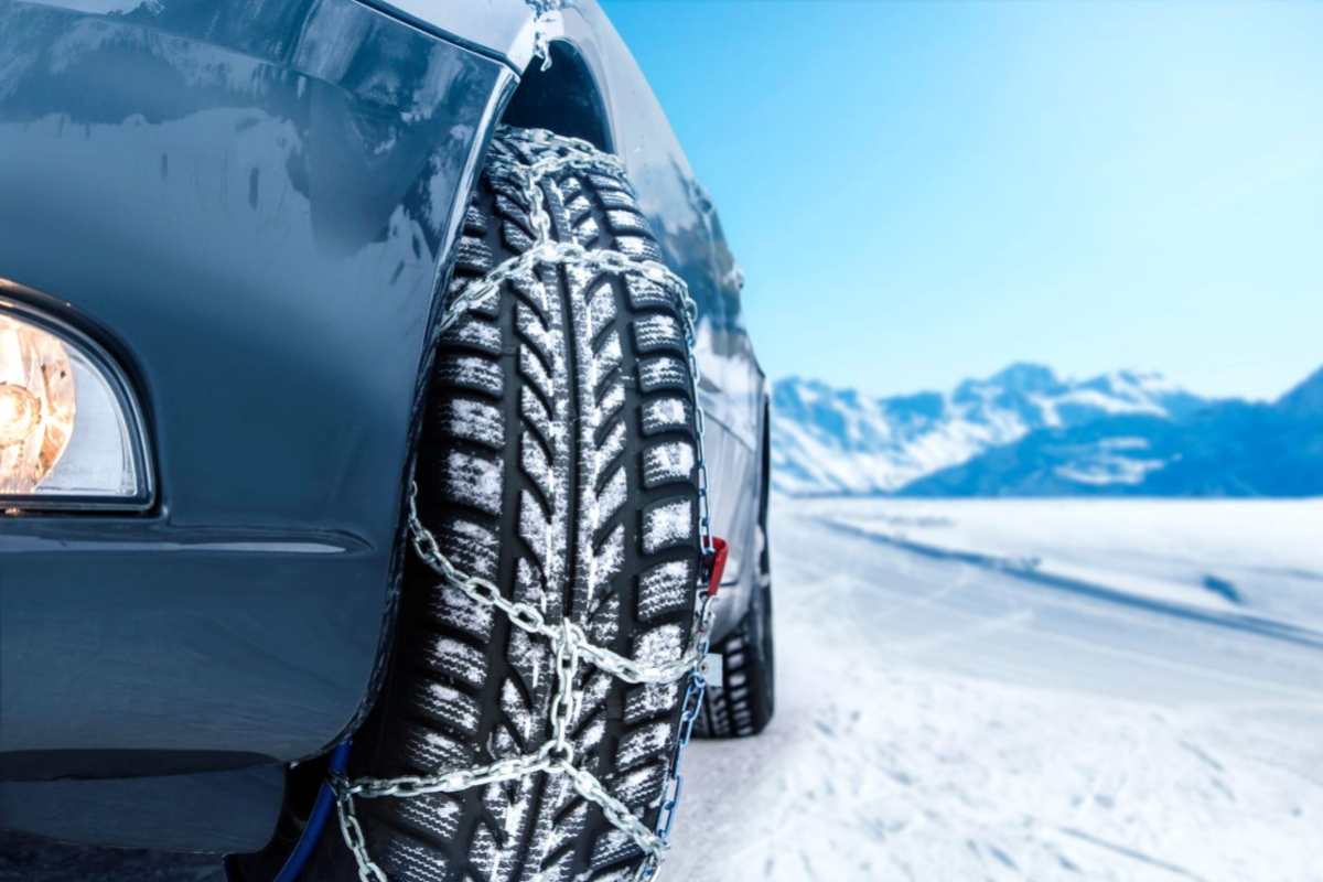 Dettaglio di un'auto con catene su fondo innevato