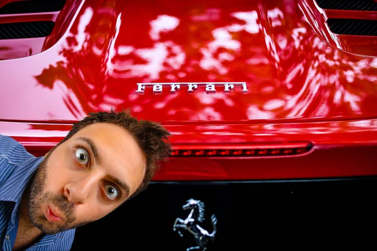 Il posteriore di una Ferrari e il viso di un uomo stupito