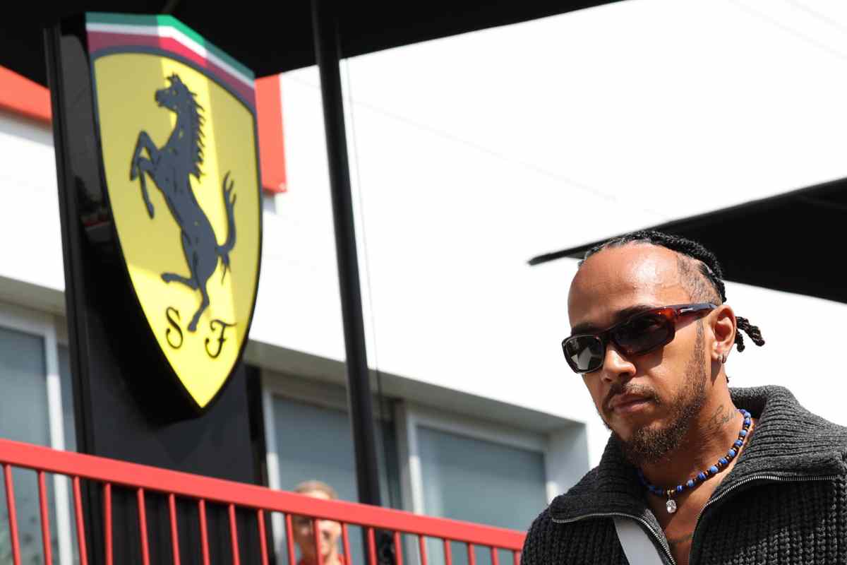 Lewis Hamilton a fianco al logo Ferrari