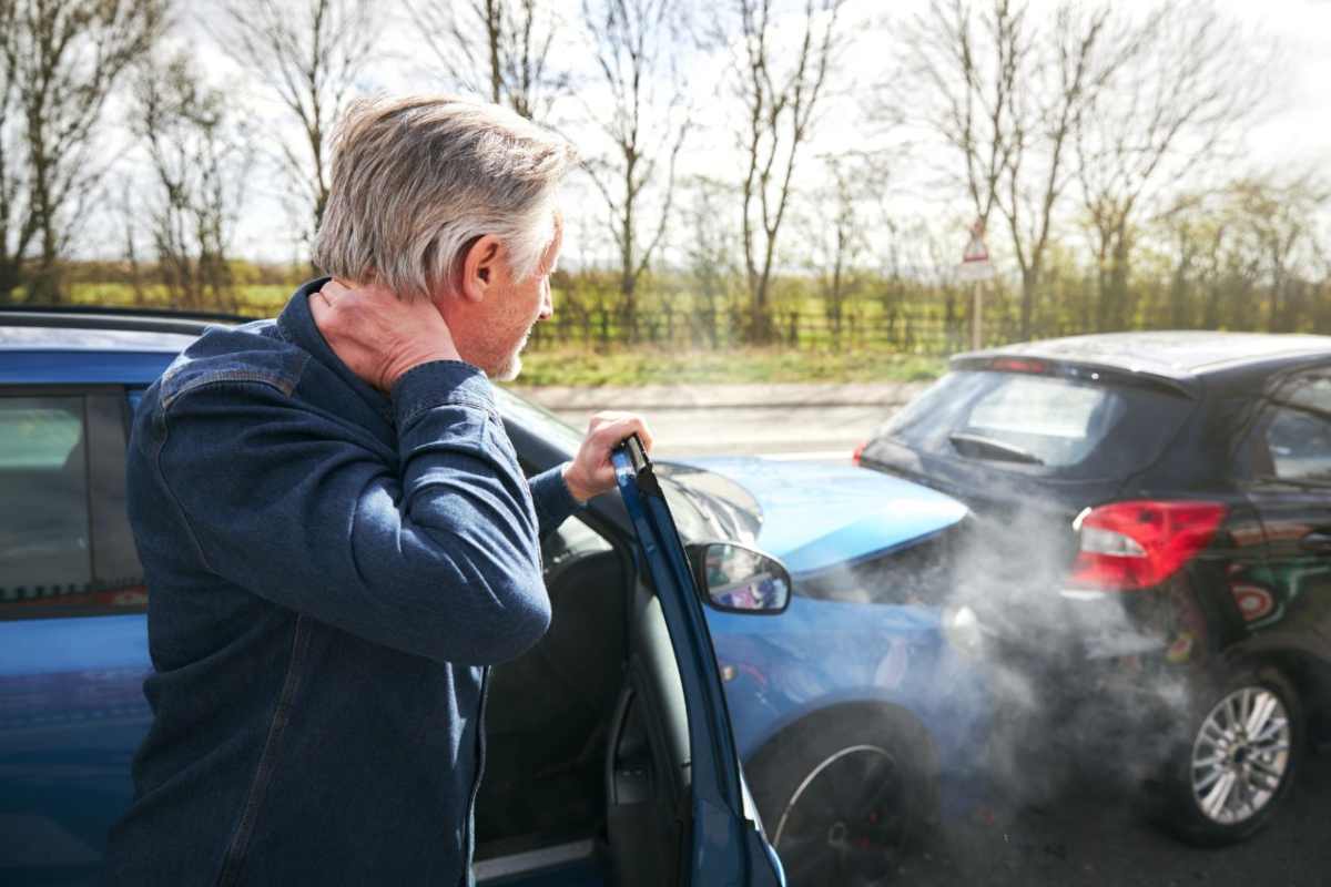 Un uomo fuori da un veicolo osserva l'incidente appena fatto