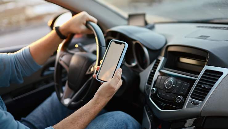 Un uomo alla guida guarda il telefono