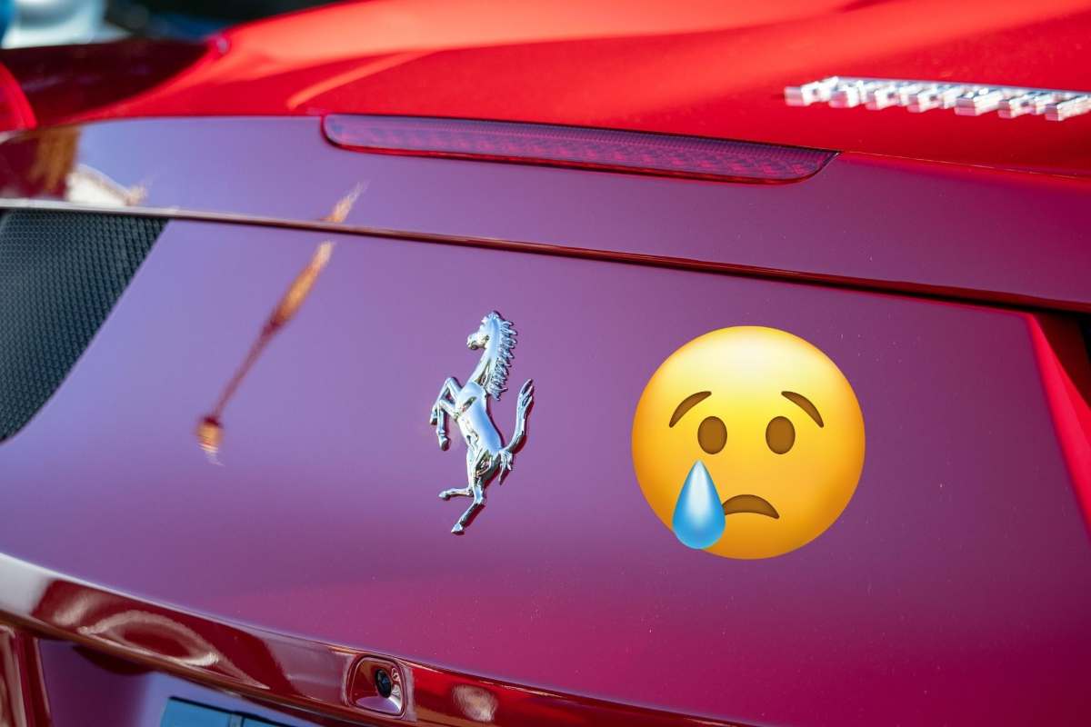 Il retro di una Ferrari con logo e a destra un emoticon che piange