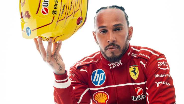 Lewis Hamilton con la tuta Ferrari e il nuovo casco in mano 