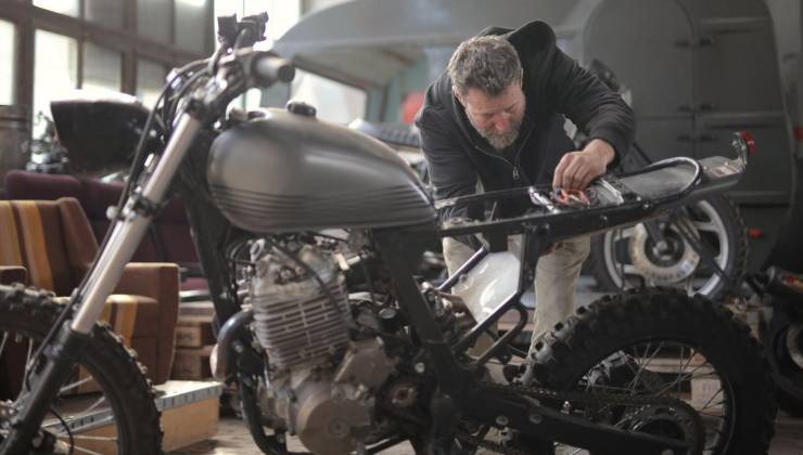 Un uomo osserva una moto in officina