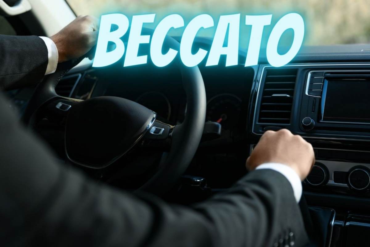 Un uomo guida un'auto e la scritta "Beccato"