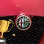 Il dettaglio del frontale di un'Alfa Romeo con logo e il disegno di una coppa con dei coriandoli