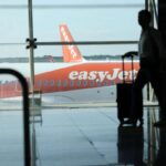 Viaggiatore con il trolley e aereo Easyjet sullo sfondo