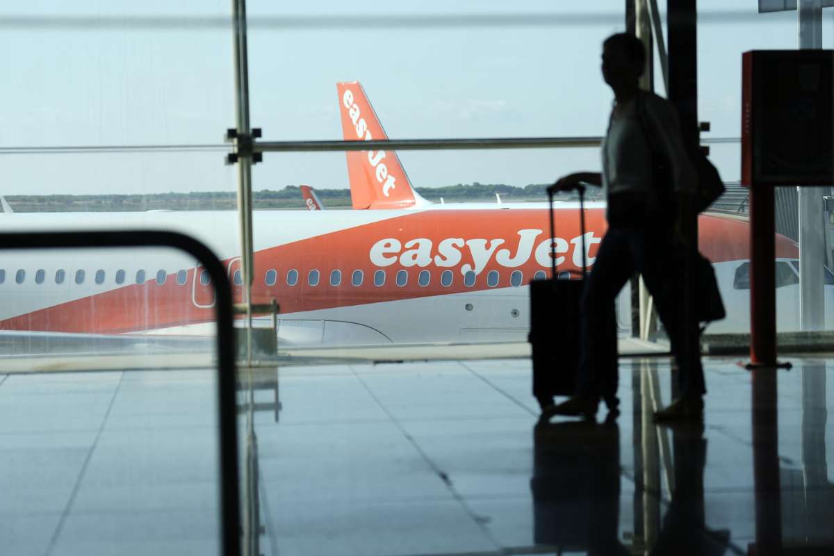 Viaggiatore con il trolley e aereo Easyjet sullo sfondo