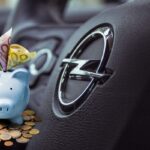 Il logo Opel e un salvadanaio con banconote e monete