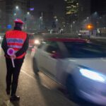Un carabiniere a bordo strada e una macchina di passaggio